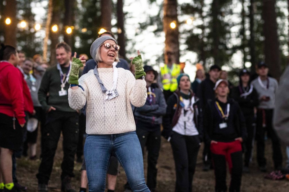 An adult scout dancing with others in the background.